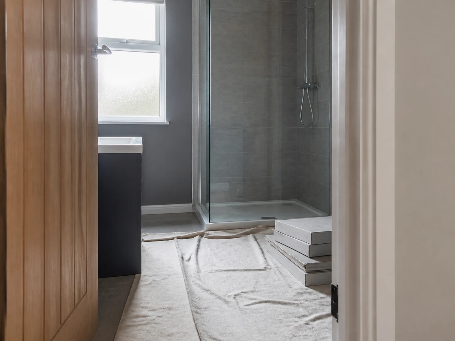 Tidy bathroom installation area with dust sheet and neatly staged materials